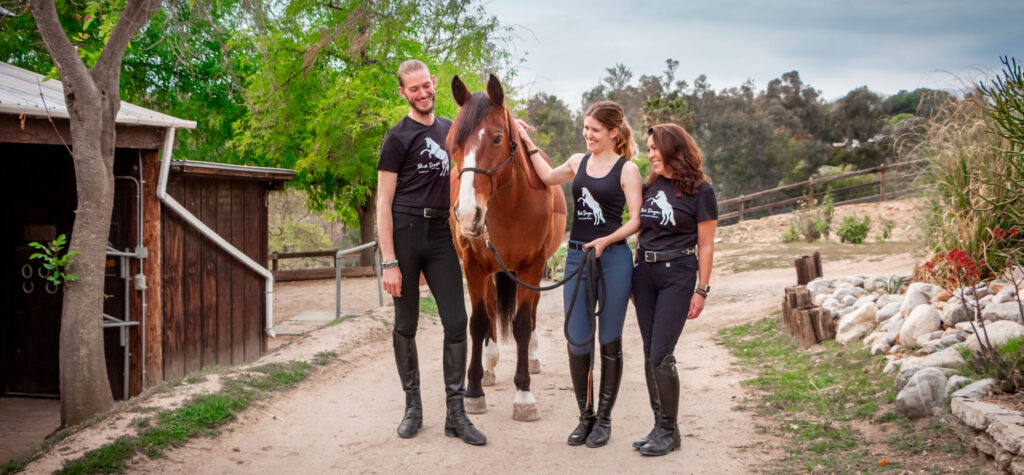 Three people in Black Dragon Bracelets shirts and a horse